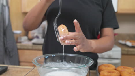 mujer glaseado donut casero sobre recipiente de vidrio en la cocina, cierre de cámara lenta