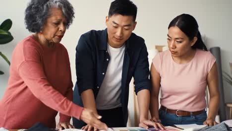 a collaborative design meeting: three individuals engaged in a color selection process, discussing fabric samples and creative ideas for a project