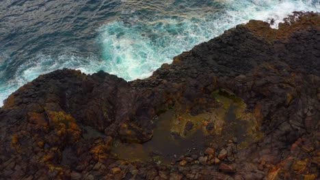 rough waves breaking against rocky cliffs of blow hole point in kiama, nsw, australia