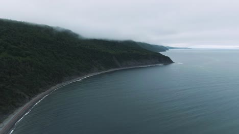 Fly-Over-The-Calm-Water-Of-Saint-Lawrence-River-By-The-Foliage-Mountain-Landscape-Of-Sainte-Anne-Des-Monts-In-Quebec,-Canada-During-Early-Morning