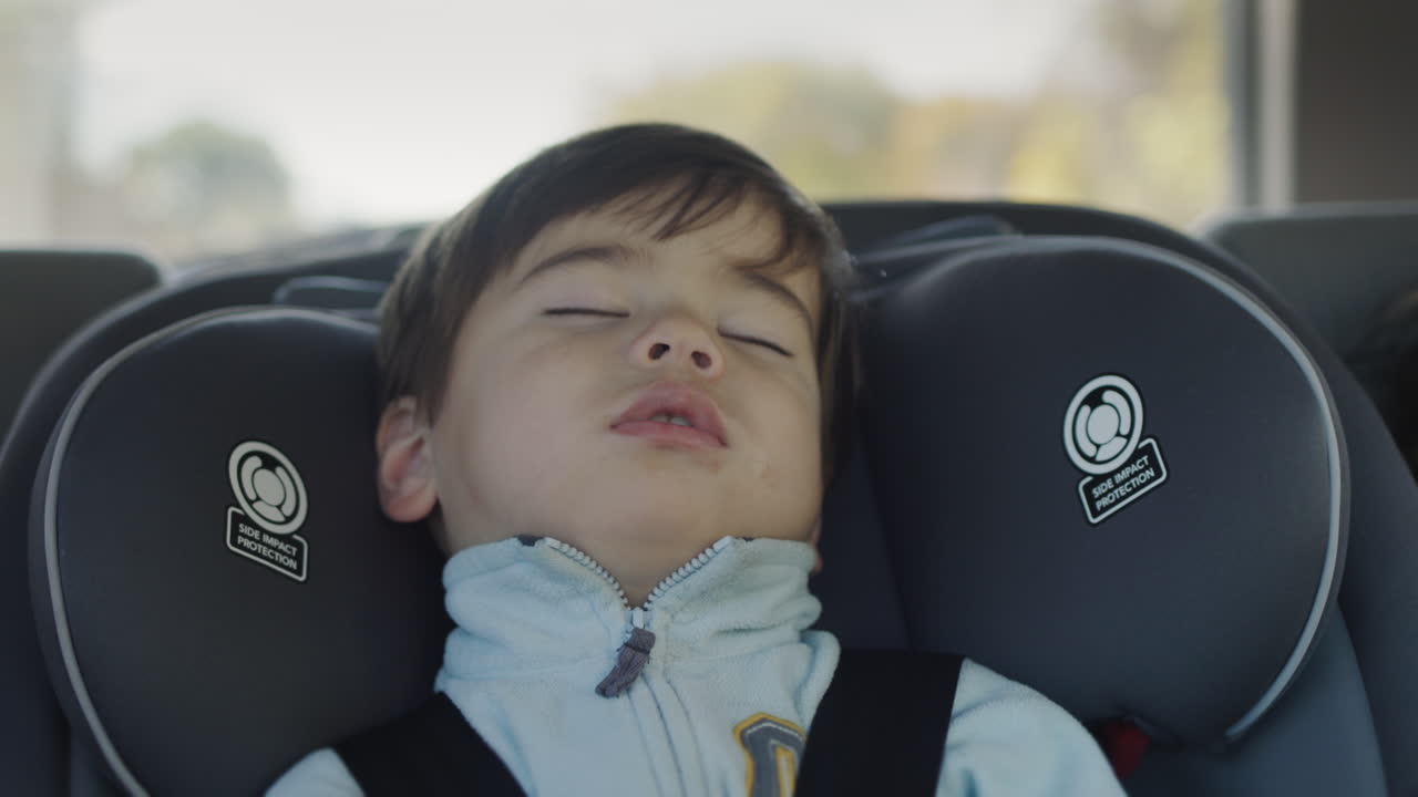 niño durmiendo en el asiento trasero del coche. bebé asiático duerme en un asiento de coche para niños