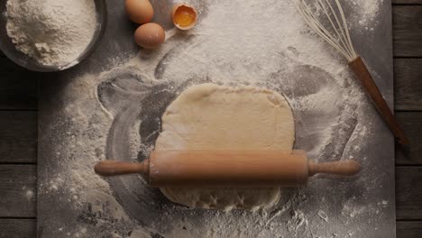 magic concept - a rolling pin itself rolls out the dough on the kitchen table against the backdrop of flour, eggs and a whisk. looped video.