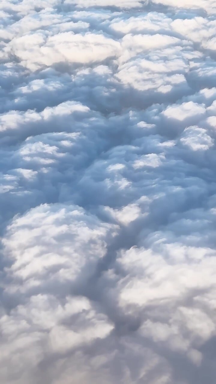Dense billowing cloud tops seen during flight high above the atmosphere, vertical airplane backdrop