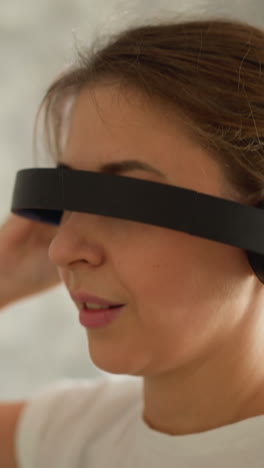 mujer oculta los ojos usando auriculares banda para la cabeza corriendo en la residencia. mujer activa disfruta de auriculares mientras hace ejercicio en la cinta de correr en el gimnasio. entrenamiento divertido