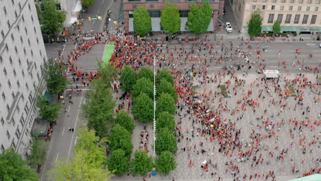 una gran multitud de manifestantes en el centro de una ciudad importante, vista aérea izquierda