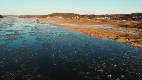 aerial shot of beautiful spring lake landscape at sunrise, frozen ice breaking on water surface