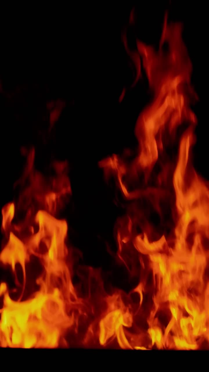 Impressionante tomada 4K contínua de uma fogueira detalhada com chamas vibrantes laranja e vermelhas sobre brasas intensas, isolada em um fundo preto puro. Perfeito para mesclagem, composição e efeitos atmosféricos