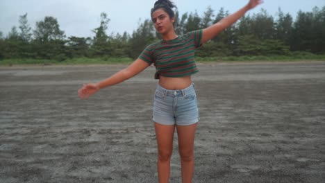 landscape view of a young woman doing stretching exercises, on a sandy beach by the ocean