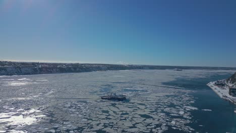 drone-shot,-boat-crossing-st-lawrence-river-in-winter-part-1