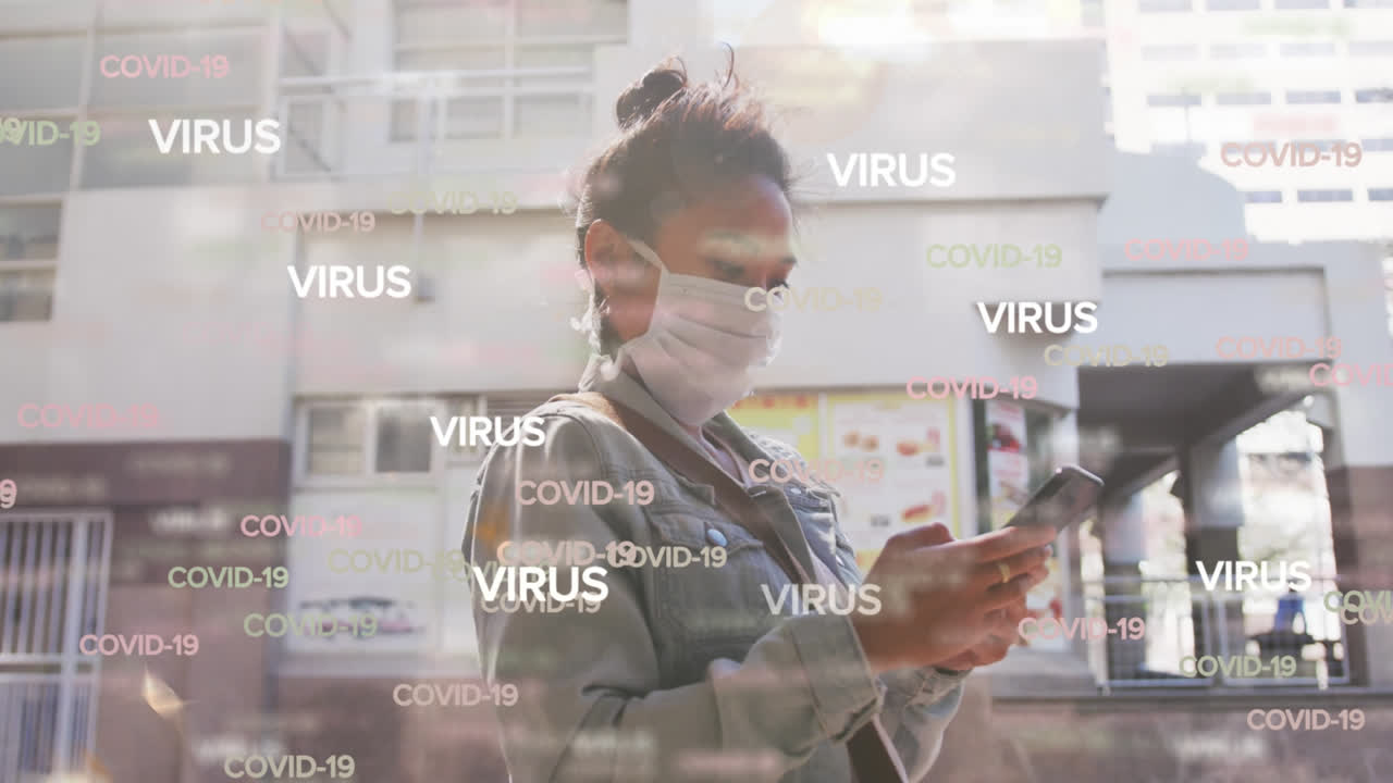 Animation of text virus and covid 19 repeated over woman in face mask using smartphone in street