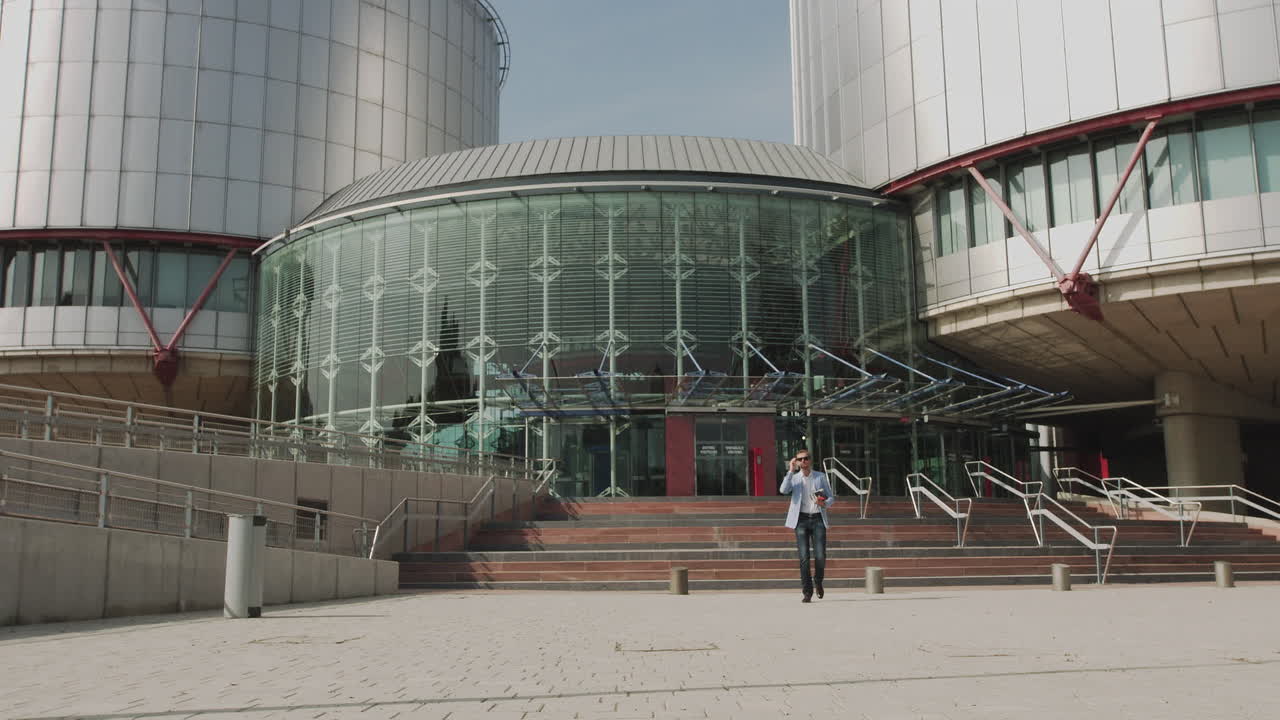 Goodlooking confident purposeful adult businessman in glasses in stylish suit going down on steps