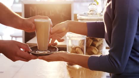 mid section of waiter serving a cup of cold coffee to customer