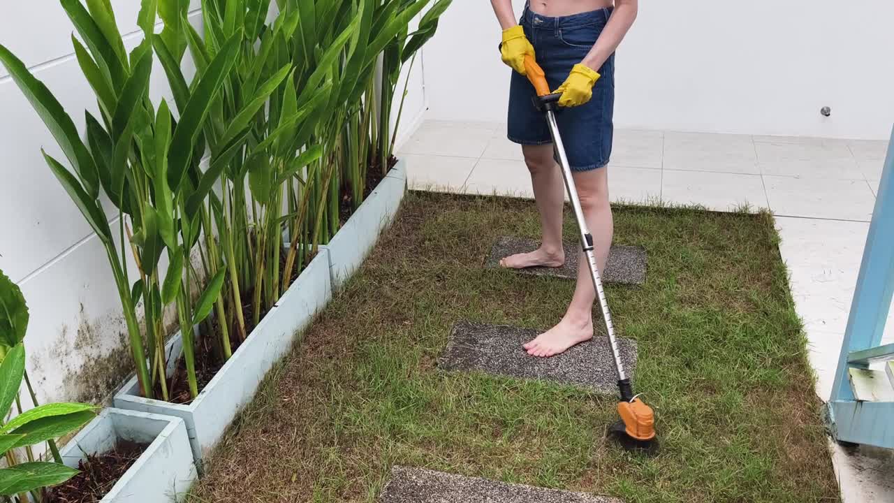 Woman Trimming Grass with Grass Trimmer