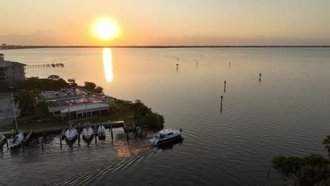 fishing-boat-cruises-out-at-sunrise,-melbourne-florida-marina-aerial