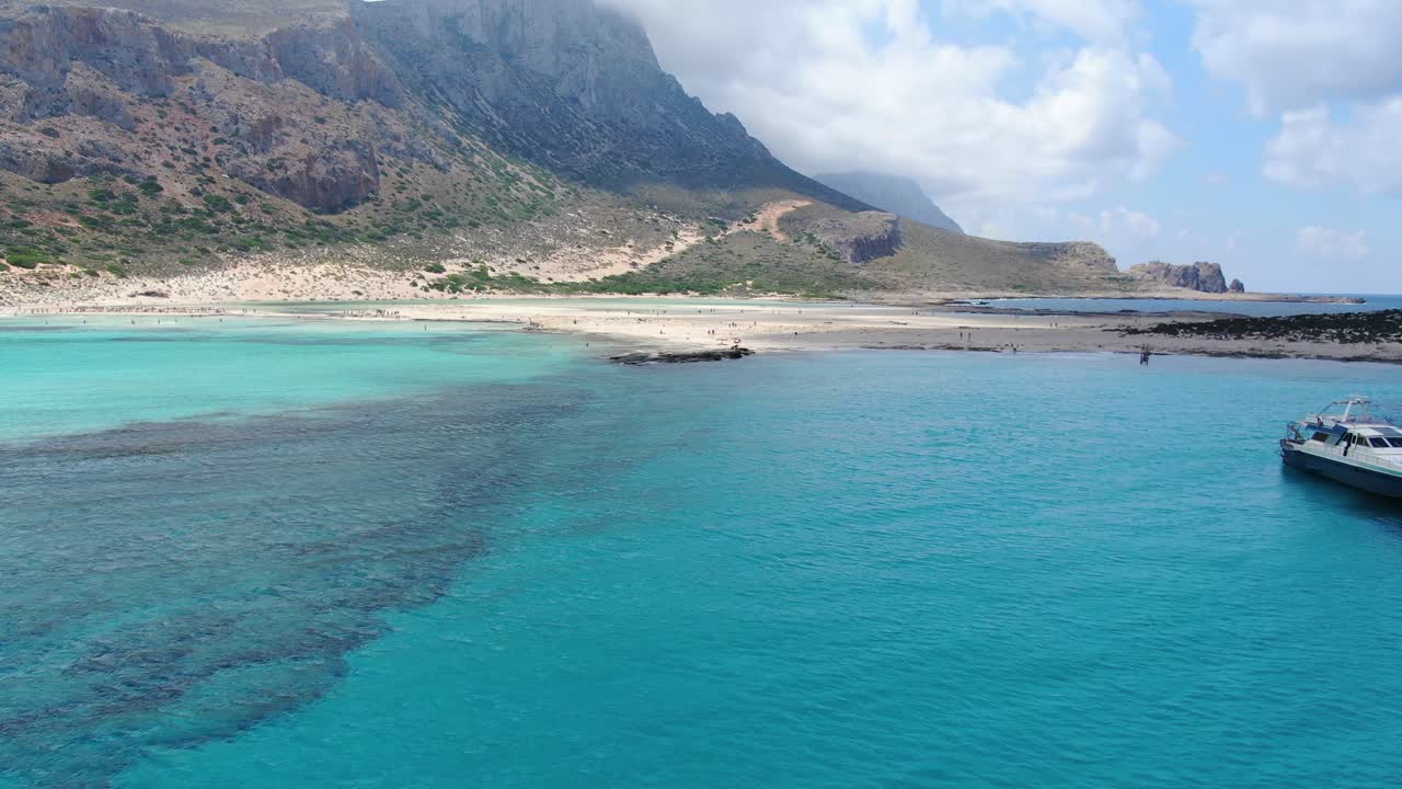 Balos Beach in Crete Greece with turquoise waters boats and mountainous background, Aerial drone flyover shot