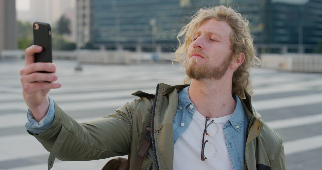 Giovane uomo che si scatta un selfie con lo smartphone in un contesto urbano