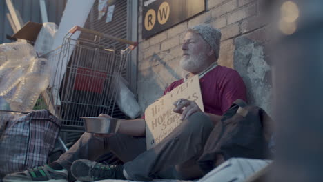 elderly beggar sitting on street, smoking and receiving donation from passerby