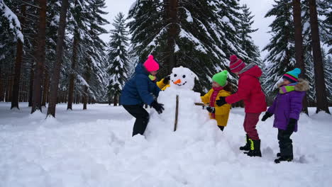 children building a snowman in a snowy forest