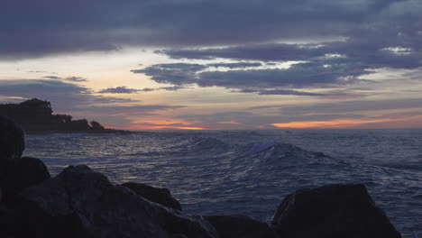 blue hour sea waves move slowly as dramatic skyline reflects in water