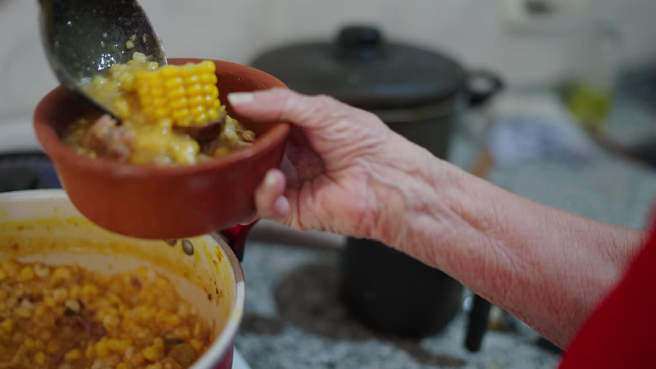 Woman's hand serving locro in dish. Traditional Argentine food. Close up