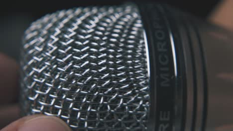 person holds modern microphone on dark background macro