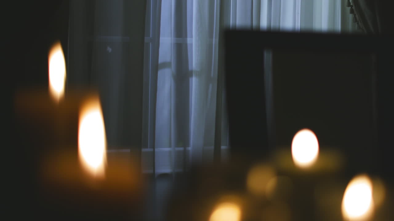 Rack focus on a group of candles illuminating a dark home during a power outage
