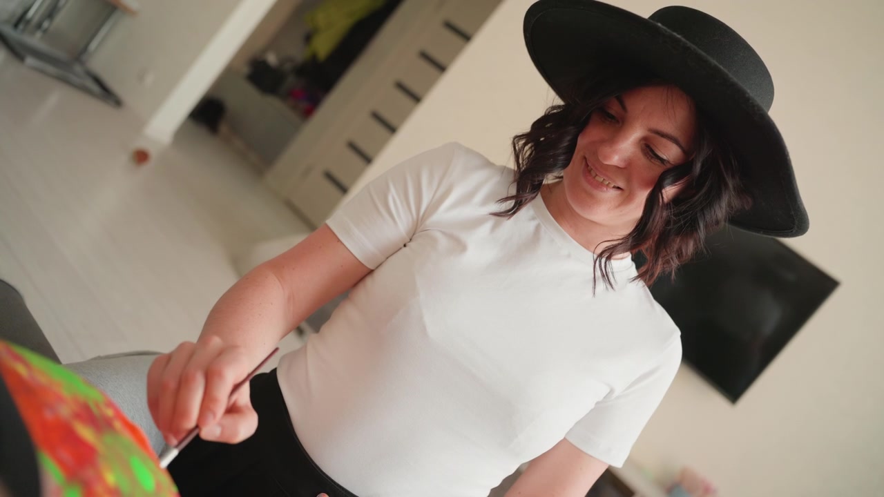 Donna creativa con un cappello nero che dipinge su tela