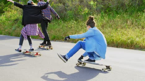 Rear-view-of-cool-young-caucasian-skateboarders-skating-on-downhill-at-countryside-4k