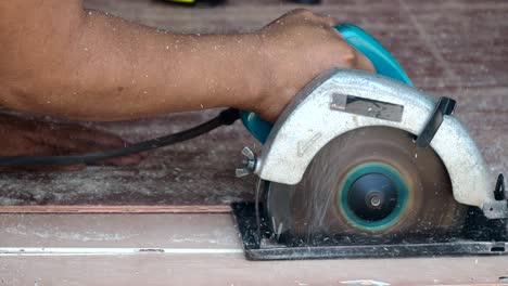 carpenter using circular saw cutting wooden board in carpentry workshop