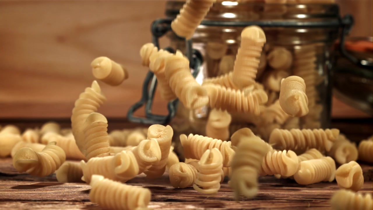 Uncooked Fusilli Pasta Falling onto a Rustic Wooden Table