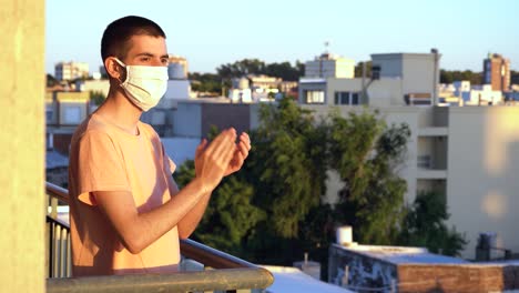 young man wearing a mask applauding health workers from the balcony