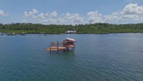 una singolare capanna di pescatore in legno su palafitte in acque poco profonde con paesaggio della giungla sullo sfondo