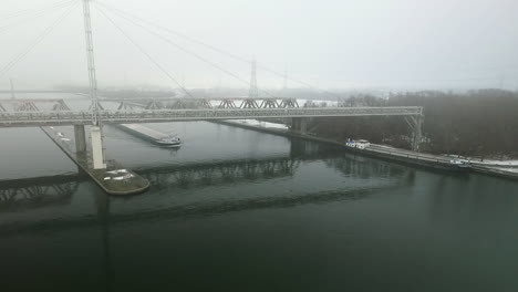 cargo ship sailing under a bridge during winter in a canal