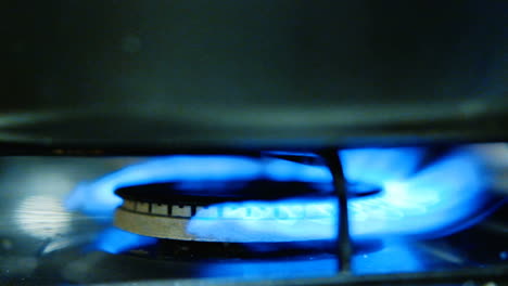 Close-up-of-a-gas-burner-igniting-with-blue-flames-on-a-stove,-slowmotion-clip