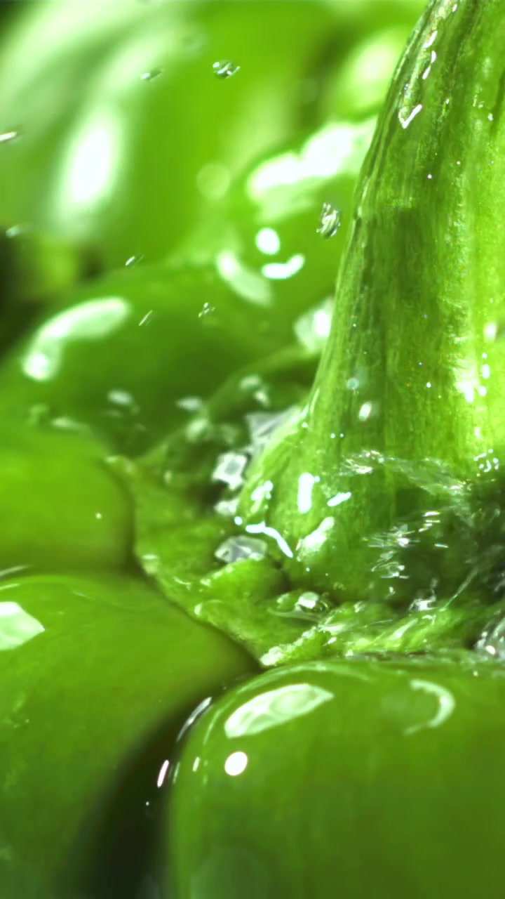 Gocce d'acqua al rallentatore che schizzano su un peperone verde fresco