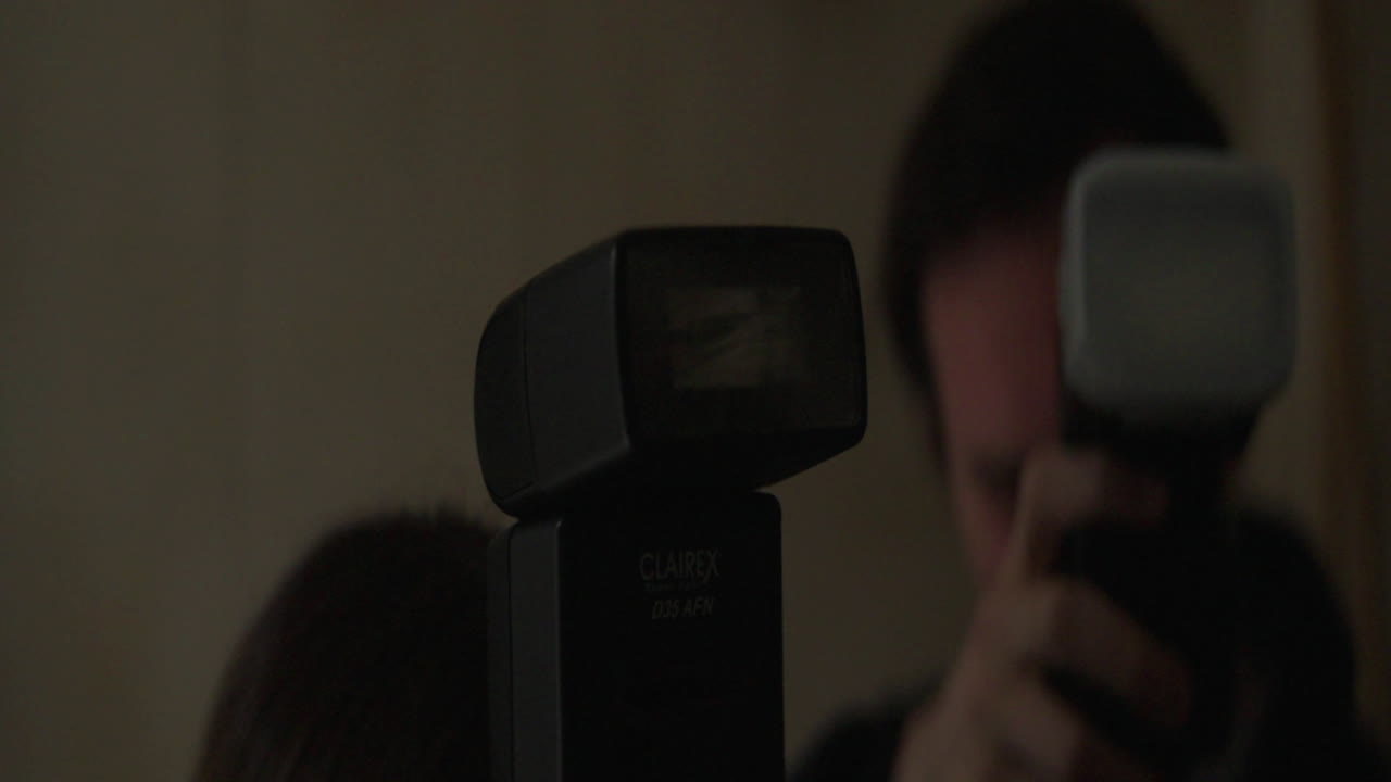 Two photographers using flashes in a dark room