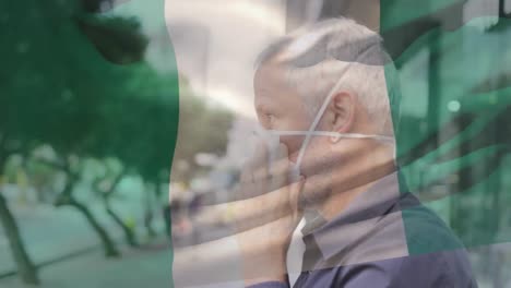 animation of flag of italy waving over man wearing face mask during covid 19 pandemic