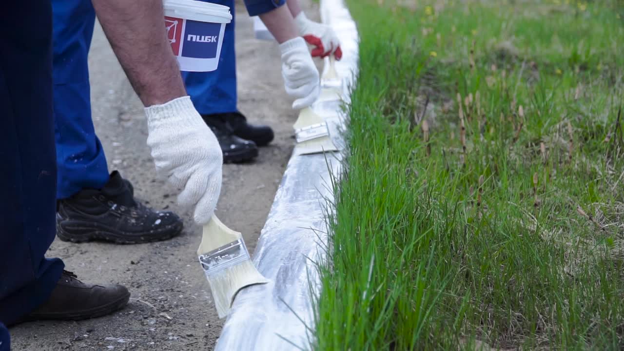 trabajadores pintando el bordillo de la carretera