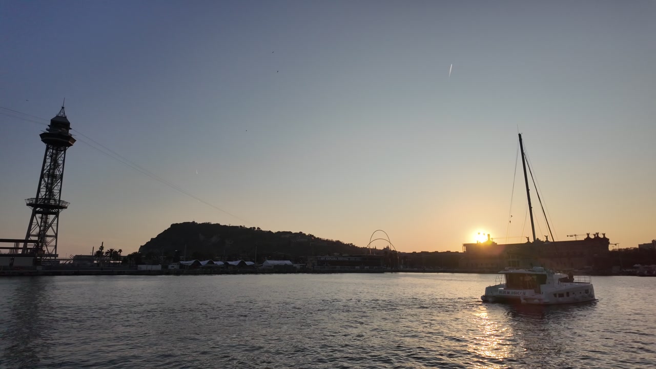 Sailboat crossing Barcelona port during sunset light
