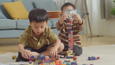 full body of asian kids assemble the construction set colorful plastic toy brick on a mat at home