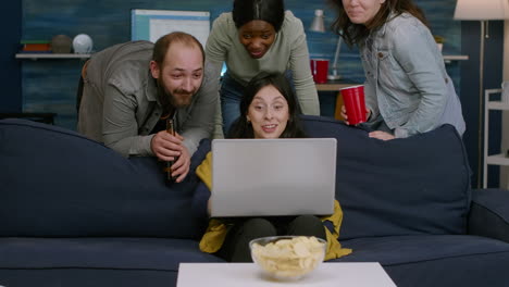 group of mixed race people chilling on couch looking at laptop computer