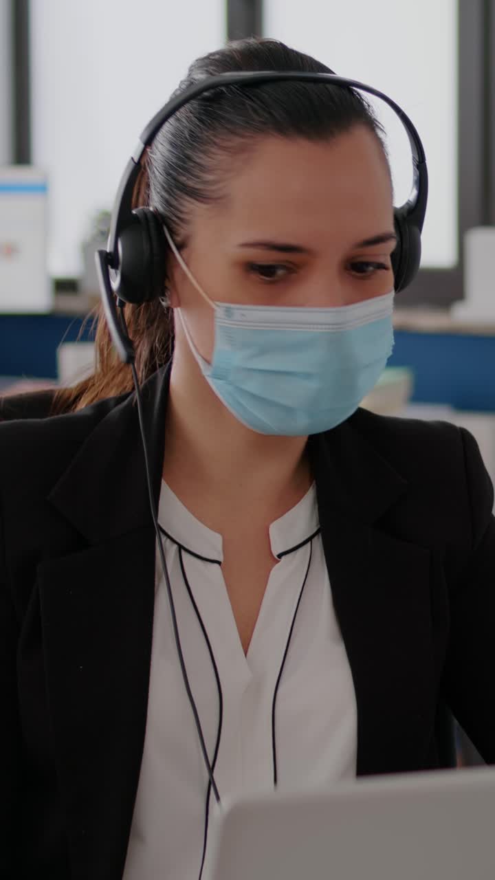 Businesswoman working with face mask and headset in the office