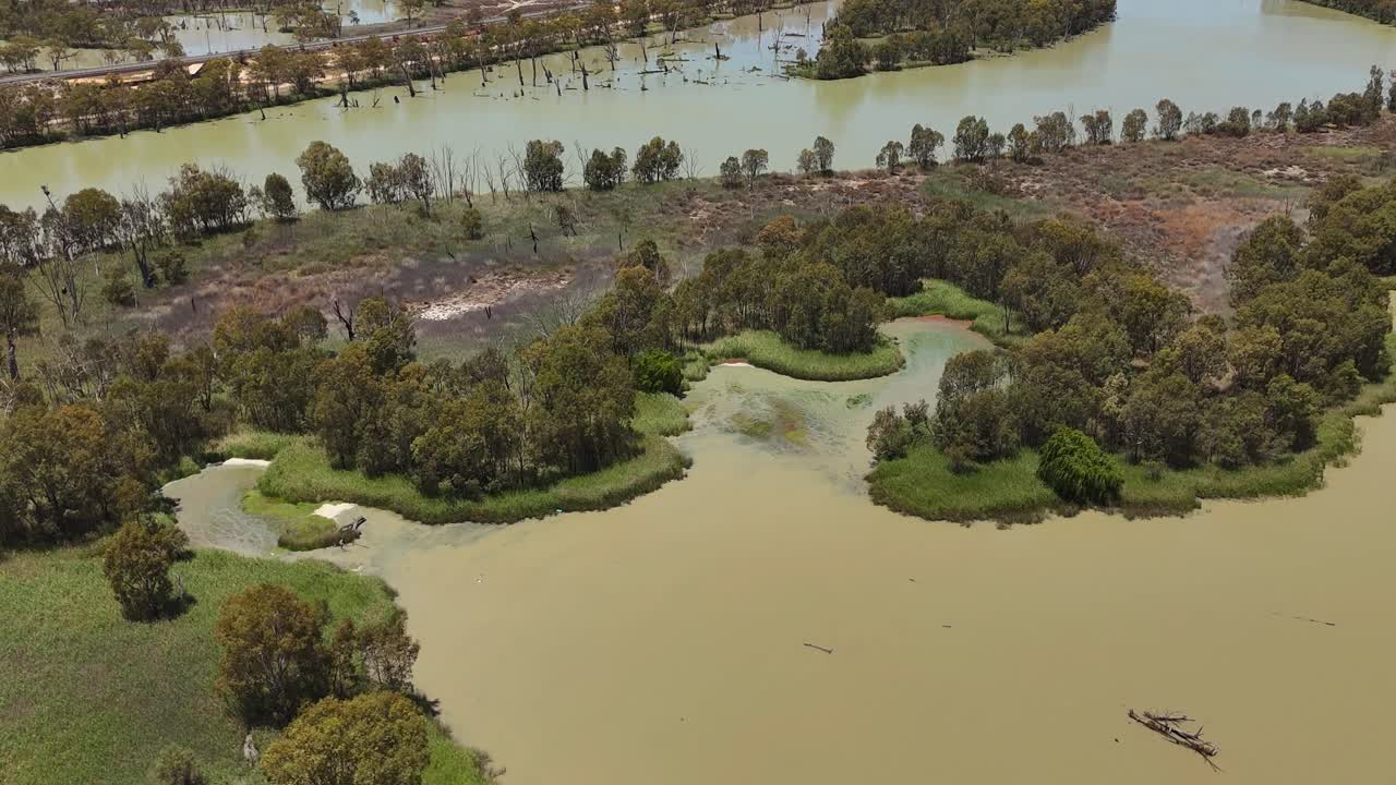 Panoramica aerea media di pozze marroni e fangose nella laguna e vegetazione vicino alla costa presso Wachtels Lagoon, alberi scoscesi