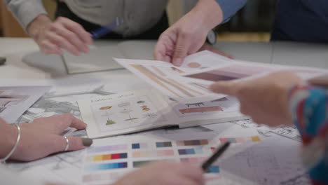 hands of colleagues discussing colors and architectural plans at office table