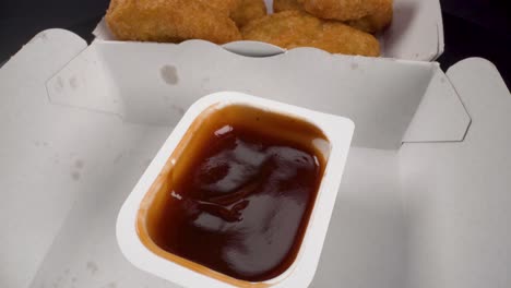 closeup view dipping a chicken nugget in barbecue sauce rotating anti-clockwise, 4k footage, fast food, fried food