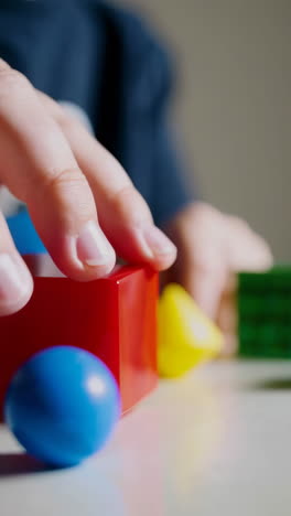 child's hand playing with colorful building blocks