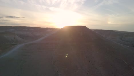 Drone-footage-of-light-peaking-over-a-mountain-in-the-Negev-Desert-during-sunset