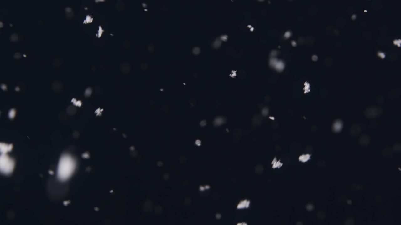 Flurry of snow on a dark January night, panning slowly down to a fence