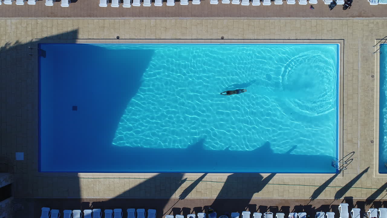 Ung mand svømmer i en pool set fra luften