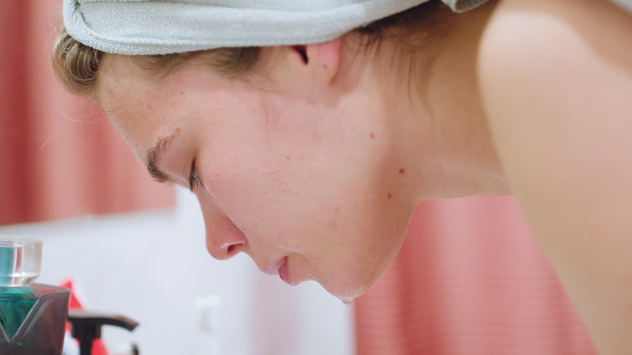 Close-up of young lady washing her face with water, gently cleaning and refreshing skin, she is focused on maintaining a clear, healthy complexion as part of her skincare routine